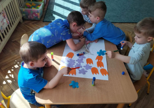 Dzieci wykonują w zespole pracę plastyczną.
