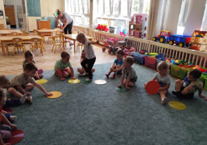 Dzieci biorą udział w zabawie z kolorowymi kołami.