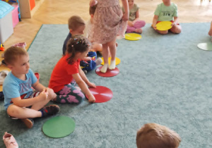 Dzieci biorą udział w zabawie z kolorowymi kołami.