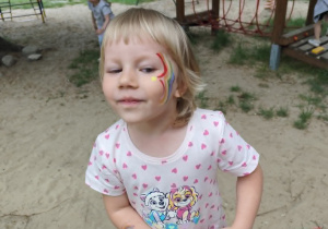 Dziewczynka prezentuje pomalowaną buzię.