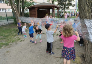 Dzieci malują farbami na stretchu.