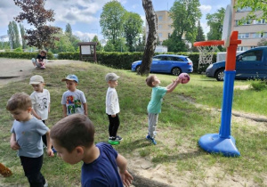 Dzieci rzucają piłką do kosza.