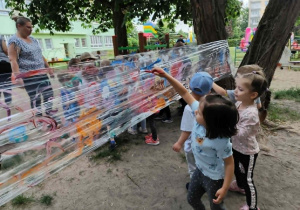Dzieci malują farbami na stretchu.