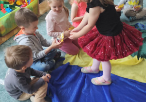 Dziewczynka częstuje dzieci cukierkami.