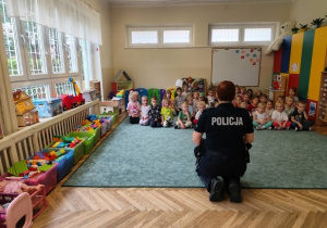 Dzieci słuchają wykładu edukacyjnego prowadzonego przez policjantkę.