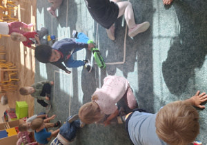 Dzieci poruszają autkami po dywanie w sali przedszkolnej