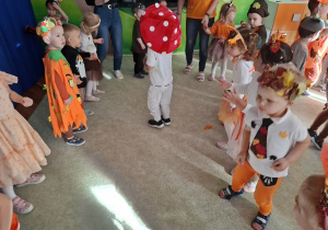 Tańczące dzieci w kole, a pośrodku dziecko w przebraniu muchomora